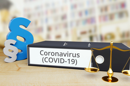 Auf einem Tisch liegt ein Ordner mit der Aufschrift „Coronavirus (COVID-19)“, daneben sind eine Waage und ein Paragrafzeichen.