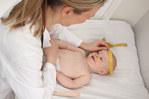 Kinderärztin misst Kopfumfang eines Babys