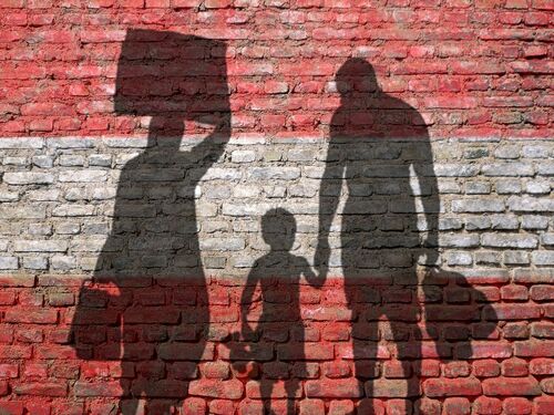Flürchtlingsfamilie vor einer rot-weiß-roten Mauer