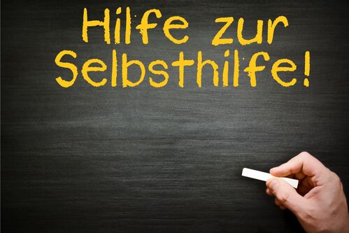 Auf einer Tafel steht: Hilfe zur Selbsthilfe