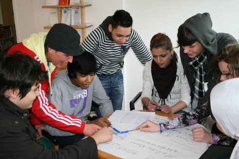 Jugendliche unterschiedlicher Herkunft sitzen auf einem Tisch