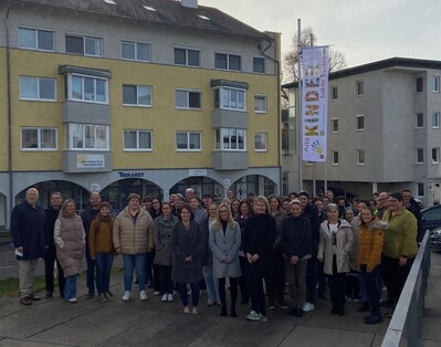 Mitarbeiterinnen und Mitarbeiter vor der Fahne