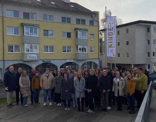 Mitarbeiterinnen und Mitarbeiter vor der Fahne