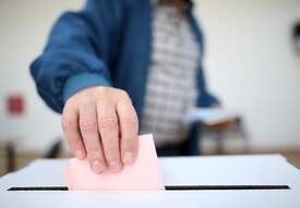 Mann wirft Stimmzettel in Urne