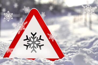 Warnschild mit Schneeflocken-Symbol und Schnee