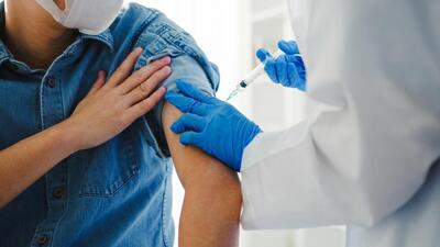 Mann bekommt eine Corona-Schutzimpfung in den Oberarm gespritzt