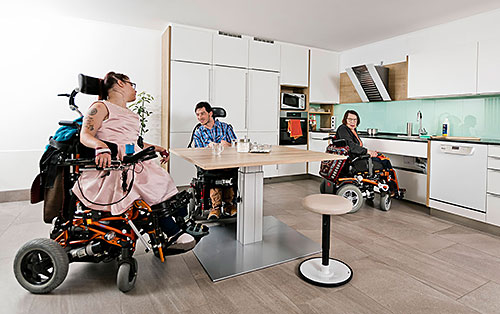 3 Rollstuhlfahrer in freundlicher Wohnküche  
