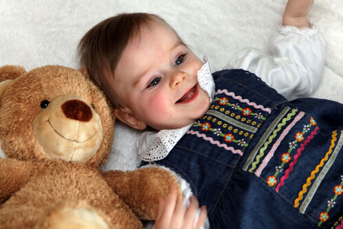 Ein kleines Kindsitzt neben seinem Teddybär 
