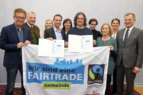 Gruppenfoto Urkundenverleihung der Fairtrade-Gemeinden mit Transparent und Urkunden