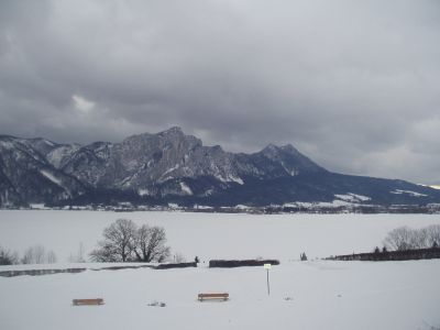 Die Drachenwand hinter dem zugefrorenen und verschneiten Mondsee