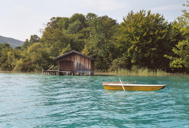 Naturnaher Uferabschnitt am Attersee mit Schilfbestand und Bootshütte