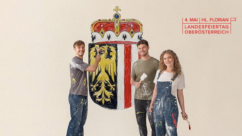 Männer und eine Frau, die gemeinsam das Oberösterreich-Wappen auf eine Wand malen. Männer und eine Frau, die gemeinsam das Oberösterreich-Wappen auf eine Wand malen.