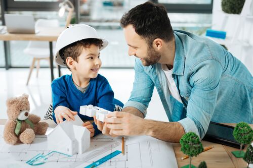 Vater und Sohn an einem Tisch mit einem Modellhaus