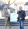 Landesrat Ing. Wolfgang Klinger und Bürgermeister Anton Froschauer vor einem großen zugedeckten Brunnen, gemeinsam halten sie eine Tafel mit der Beschriftung Neptun Wasserpreis, Perg ist Oberösterreichs Wassergemeinde 2021