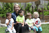 Landeshauptmann-Stellvertreterin Mag.a Christine Haberlander sitzt mit vier Kindern auf einer Bank in einem Garten
