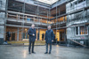 Landeshauptmann Mag. Thomas Stelzer und Landesrat Dr. Wolfgang Hattmannsdorfer stehen nebeneinander vor einem im Bau befindlichen eingerüsteten mehrstöckigen Haus