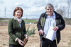 Landesrätin Michaela Langer-Weninger mit jungem Bäumchen und DI Christoph Jasser mit Spaten stehen nebeneinander auf einem Feld