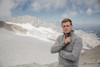 Landesrat Stefan Kaineder steht in einer winterlichen Hochgebirgslandschaft, im Hintergrund ein Gletscher, Schnee, Felsen