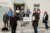 Christian Denkmaier und Landesrat Stefan Kaineder vorne, sie halten eine Schild mit Beschriftung Bienenfreundliche Gemeinde. Dahinter Thomas Arnfelser, Peter Edelbauer, Markus Barth, Roger Jagersberger, Markus Kumpfmüller, Andrea Wagner und Gerlinde Larndorfer auf den Eingangsstufen eines Gebäudes