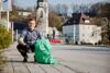 Landesrat Stefan Kaineder mit einem Abfallsackerl mit der Aufschrift „Hui statt Pfui“, im Hintergrund Markplatz mit Kirche