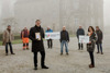 Karl Billinger, Alfred Hurt, Landesrat Stefan Kaineder, Kurt Rothbauer, Josef Dieplinger, Markus Kumpfmüller, Daniela Frauscher und Margit Zauner, vor dem Kunsthaus, der Landesrat hält eine Tafel mit Aufschrift Bienenfreundliche Gemeinde und einen Sack mit Saatgut in Händen