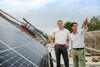 Landesrat Stefan Kaineder und Lukas Hader stehen auf einem Dach, auf dem zahlreiche Photovoltaik-Anlagen montiert sind