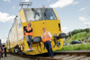 Ministerin Leonore Gewessler und Landesrat Stefan Kaineder, beide mit Warnwesten, stehen auf einer Gleisanlage direkt vor einer Lokomotive/Zugmaschine