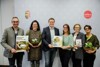 Bürgermeister Peter Zieher aus Frankenmarkt, Monika Brandner vom Umweltausschuss Frankenmarkt, Umwelt- und Klima-Landesrat Stefan Kaineder, Gerlinde Larndorfer vom Bodenbündnis OÖ, Lucia Göbesberger von der Diözese Linz, und Paula Polak von Wilde Blumen, stehend mit Gartenbroschüren und Blumentöpfen in den Händen.