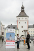 Mag.a Dr.in Elisabeth Kölblinger mit Landesrat Stefan Kaineder auf dem Hauptplatz in Vöcklabruck, gemeinsam halten sie eine Kiste mit Lebensmitteln