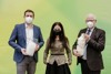 Landesrat Stefan Kaineder, Veronika Bohrn Mena und Peter Hildebrand, alle mit FFP2-Masken, stehen nebeneinander und halten zwei große Glasgefäße, in denen sich Baumwolle bzw. Daunen befinden