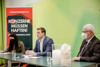 Veronika Bohrn Mena, Landesrat Stefan Kaineder und Peter Hildebrand sitzen in großem Abstand nebeneinander an einem Konferenztisch, auf dem zwei große Glasgefäße mit Baumwolle bzw. Daunen stehen, im Hintergrund Rollplakat mit Beschriftung Lieferkettengesetz.at, Konzerne müssen haften! Lieferkettengesetz jetzt!