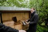Landesrat Stefan Kaineder bei einem Bienenhaus mit mehreren Bienenstöcken aus Holz