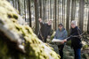 Landesrat Stefan Kaineder, Gerald Zauner und Richard Königseder mit einer Landkarte, nebeneinander in einem Wald