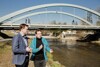 Landesrat Stefan Kaineder und DI Franz Gillinger (Chef des Gewässerbezirkes Linz und Wasserbauexperte)  stehen nebeneinander und reden miteinander; rechts von ihnen ist ein Fluss, hinter ihnen eine Brücke zu sehen. 