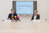 Landesrat Stefan Kaineder und Mag. Christoph Hofinger sitzen an einem Konferenztisch mit Mikrofonen und Namensschildern, hinter ihnen eine Videowand mit Beschriftung Das sagt Oberösterreich zu aktuellen Fragen der Klima- und Energiepolitik 2023