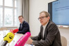 Landesrat Stefan Kaineder und Mag. Christoph Hofinger sitzen an einem Konferenztisch, Christoph Hofinger spricht, vor ihm Mikrofone