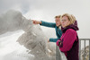 Landesrat Stefan Kaineder und Leonore Gewessler stehen nebeneinander am Geländer einer Aussichtsplattform, LR Kaineder zeigt ins Gelände, im Hintergrund Gletscher, Felsen
