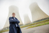 Landesrat Stefan Kaineder steht mit verschränkten Armen vor den Kühltürmen eines Atomkraftwerkes