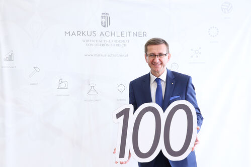 Wirtschafts-Landesrat Markus Achleitner hält ein Schild in Form eines Hunderters
