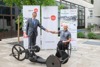 Landesrat Markus Achleitner und Walter Ablinger geben sich einen Gruß mit der Faust, vor ihnen ein Paracycling-Sportrad, hinter ihnen Plakate mit Werbung für die Europameisterschaften