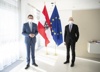 Landesrat Markus Achleitner und Minister Dr. Martin Kocher, beide mit FFP2-Maske, im Hintergrund Österreich- und EU-Fahne