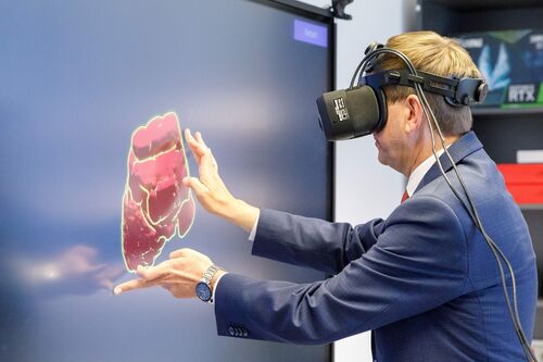 Landesrat Markus Achleitner mit Virtual-Reality-Brille berührt ein Display, auf dem ein unregelmäßiges Gebilde dargestellt ist