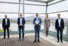 Raphael Friedl, Klaus Grübl, Wirtschafts-LR Markus Achleitner - er hält eine Plakette in der Hand -, Nora Mack und Fabian Lichtenstein stehen in einem Gebäude vor einer Glasfront, dahinter ein Fluss mit Stadt und Landschaft.