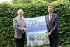 v.l.: LR Max Hiegelsberger und LR Markus Achleitner stehen vor einem grünen Blätterzaun und sie halten ein Plakat „falstaff / Oberösterreich Zeit für echten Genuss“ in den Händen.