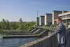 Wirtschafts- und Energie-Landesrat Markus Achleitner stützt sich an einer Mauer ab; rechts daneben ist das Wasserkraftwerk Marchtrenk zu sehen.