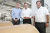 Gilles Michel, Landesrat Markus Achleitner und Thomas Ebetshuber stehen nebeneinander in einer Betriebshalle, vor ihnen riesige Papierrollen