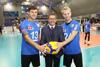 Tomek Rutecki, Landesrat Markus Achleitner und Markus Berger stehen nebeneinander in einer Sporthalle mit Zuschauertribünen und halten gemeinsam einen Volleyball 