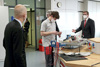 Arbeitsminister Martin Kocher und Landesrat Markus Achleitner mit einem Lehrling in einer Lehrwerkstatt, auf einer Werkbank Elektronik-Bauteile