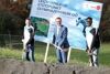 Susanne Walli, Landesrat Markus Achleitner und Endi Kingley mit Spaten voller Sand, im Hintergrund Plakat mit Foto und Aufschrift Leichtathletik-Stützpunkt Olympiazentrum OÖ