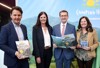 v.l.: Mag. Andreas Winkelhofer, Petra Riffert, LR Markus Achleitner und Herta Wiedlroither stehen vor einem Plakat mit einem Berg und einer Sonne und der Aufschrift Camping.